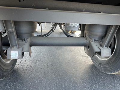 Rear view of a 2026 Utility 3000R trailer hitch area showing tandem axles, suspension, air lines, and frame crossmember.