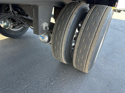 Dual tires on a Utility 3000R trailer undercarriage with suspension components and wheel hubs visible.