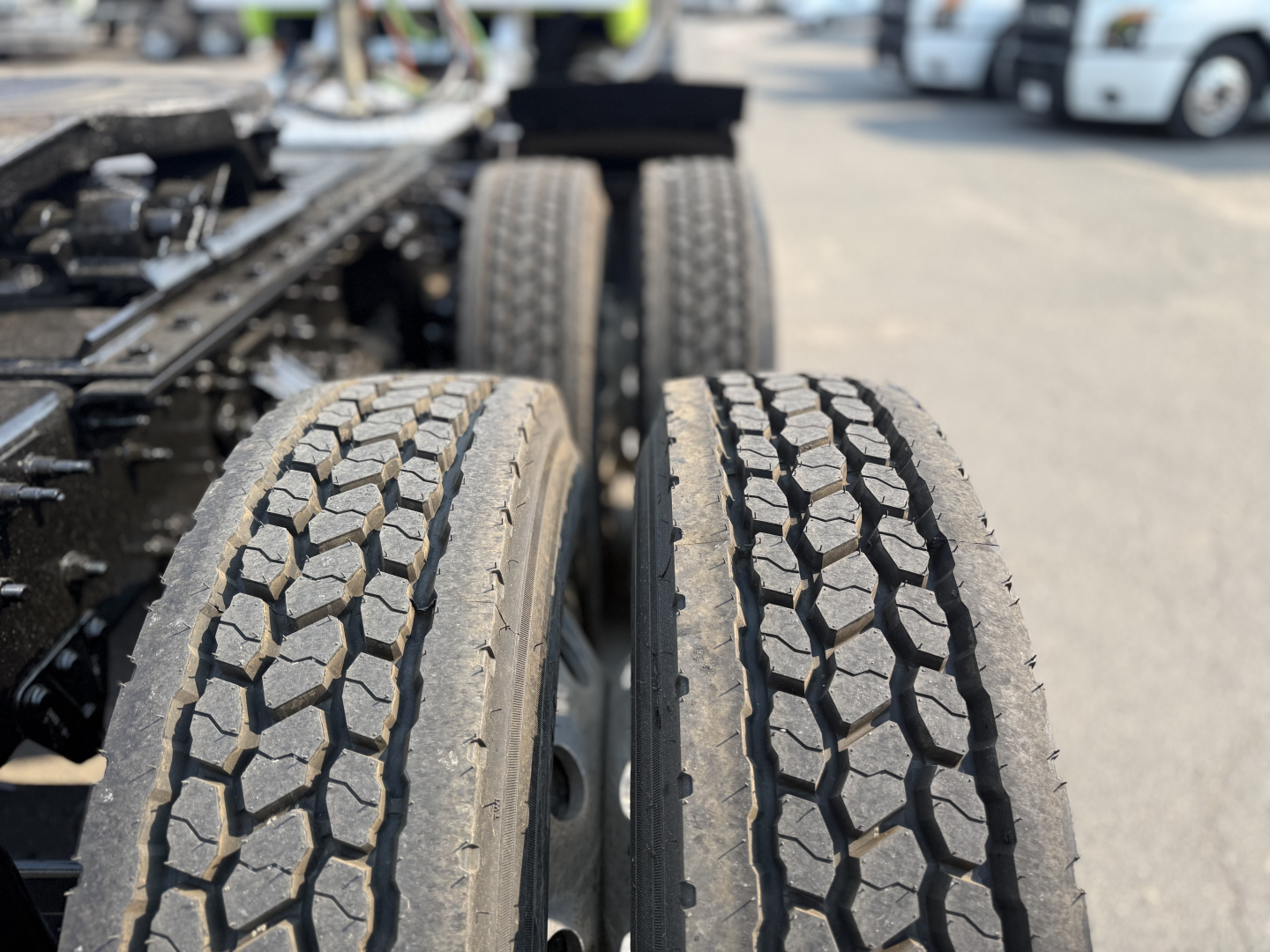 Two large truck tires on a Mack AN64T chassis with other trucks in the background.