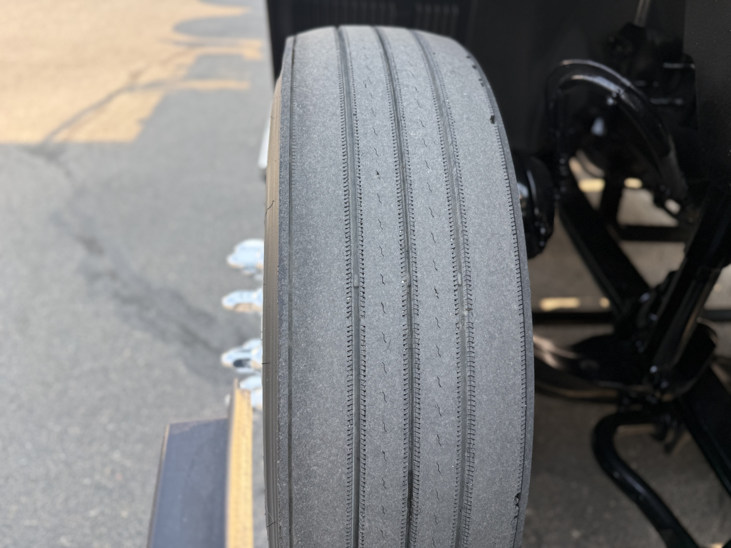 Mack AN64T truck front tire view showing tread and wheel well, with suspension components visible in background.