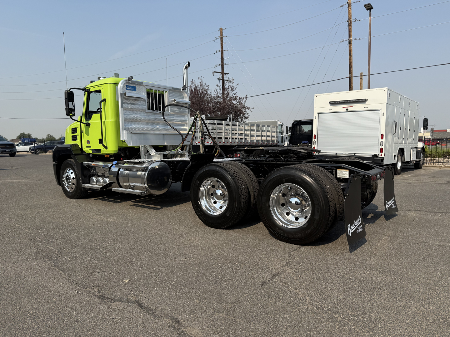 Truck chassis showing Mack AN64T cab and dual rear axles with aluminum tank and utility box in yard.