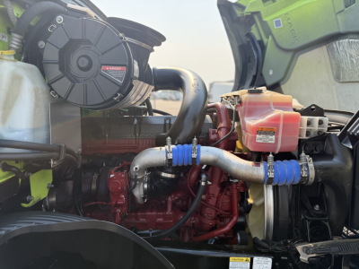 Mack AN64T engine bay showing air filter housing, turbo/intercooler piping, coolant reservoir in pink, blue silicone hoses, red engine block, and radiator area