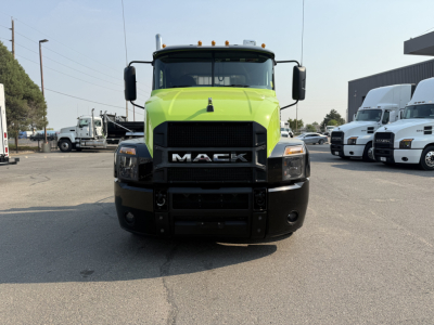 Front view of a lime-green Mack AN64T daycab truck with black bumper and grille in a dealership lot.