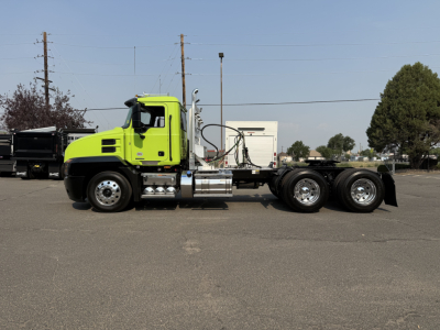 Mack AN64T conventional daycab truck side view with lime green cab and chassis showing fuel tanks, chrome exhaust stack, and drivetrain,