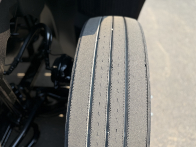 Tire tread close-up on a Mack AN64T daycab truck showing front drive tire with detailed grooves and vertical wear indicators.