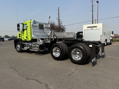 Truck chassis showing Mack AN64T cab and dual rear axles with aluminum tank and utility box in yard.
