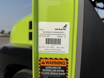 VIN label on a green Mack AN64T showing VIN 1M1AN4GY4SM048802 and gross weight 16260 lb with a warning sticker below about entering and exiting to avoid serious injury.