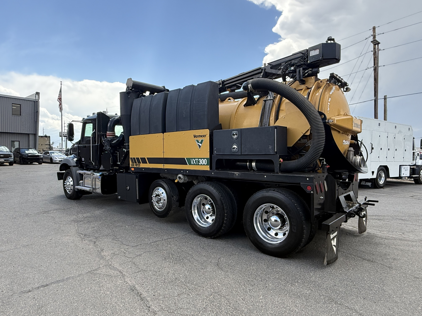 Truck side view of a 2023 Mack GR64B vacuum truck with a large yellow and black compressor unit, hoses, and hose reel. Visible label reads 'VIODE' or 'VAX' on the side; multiple compartments and a crane-like device on top.