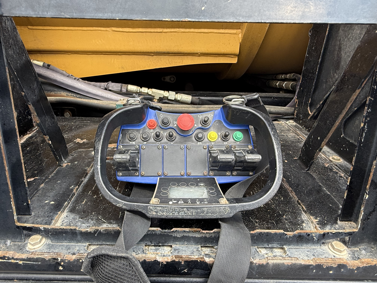 Mack GR64B control panel with red, green, and yellow buttons and joystick handles, wiring and hydraulic lines visible in machinery bay.
