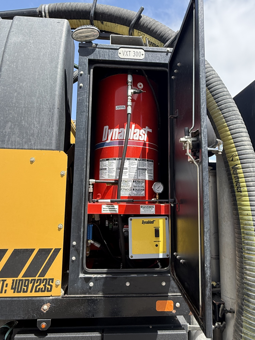 Rear cabinet showing a red Dynastat fire extinguisher mounted inside a black compartment with yellow exterior paneling and hoses.