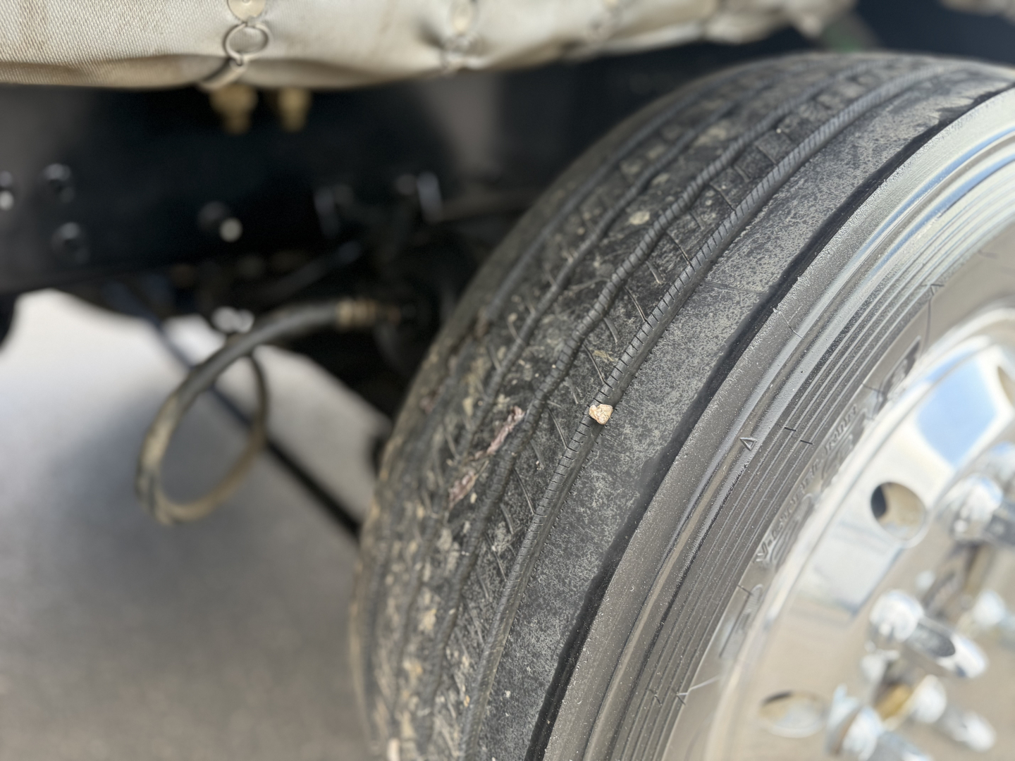 Mack GR64B truck front wheel and suspension view showing tire tread and chassis components.