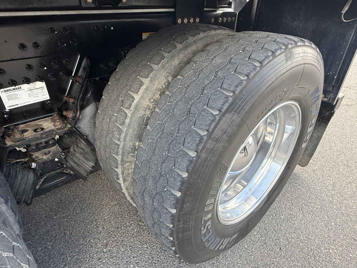 Mack GR64B truck rear dual wheel assembly showing tire tread and wheel, with chassis and suspension components visible.