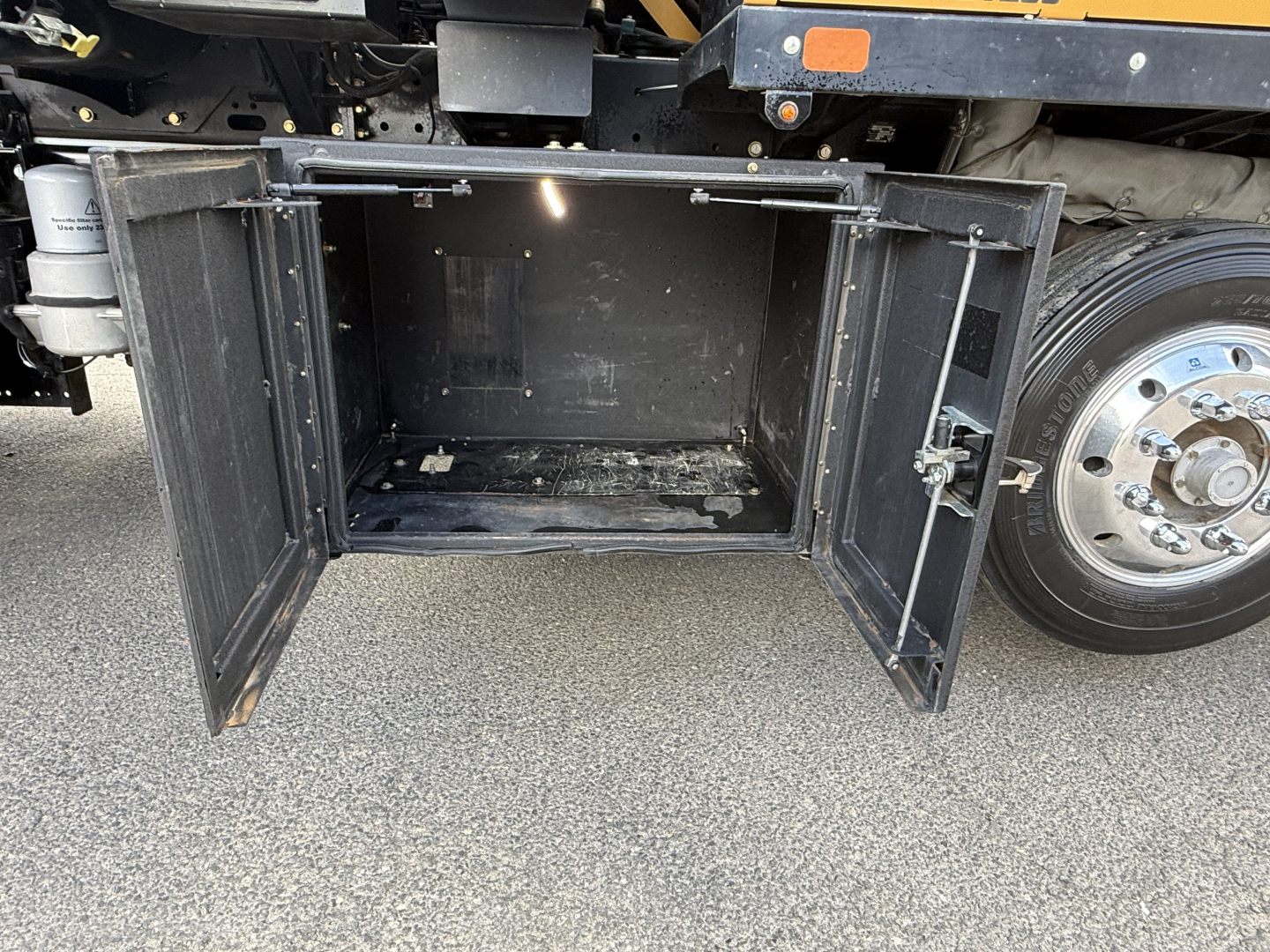 Rear storage compartment doors open showing empty cargo area under Mack GR64B truck chassis.
