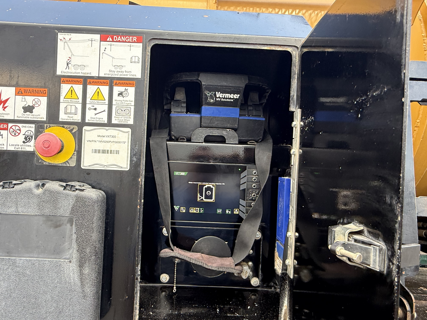 Industrial generator or compressor unit with Vermeer control panel in the open hatch; warning label cluster on left, red emergency stop button, and blue/black housing visible.