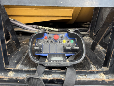 Mack GR64B control panel with red, green, and yellow buttons and joystick handles, wiring and hydraulic lines visible in machinery bay.
