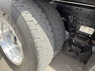 Mack GR64B truck rear dual wheels and suspension showing tire tread and axle components with a sticker on the chassis.