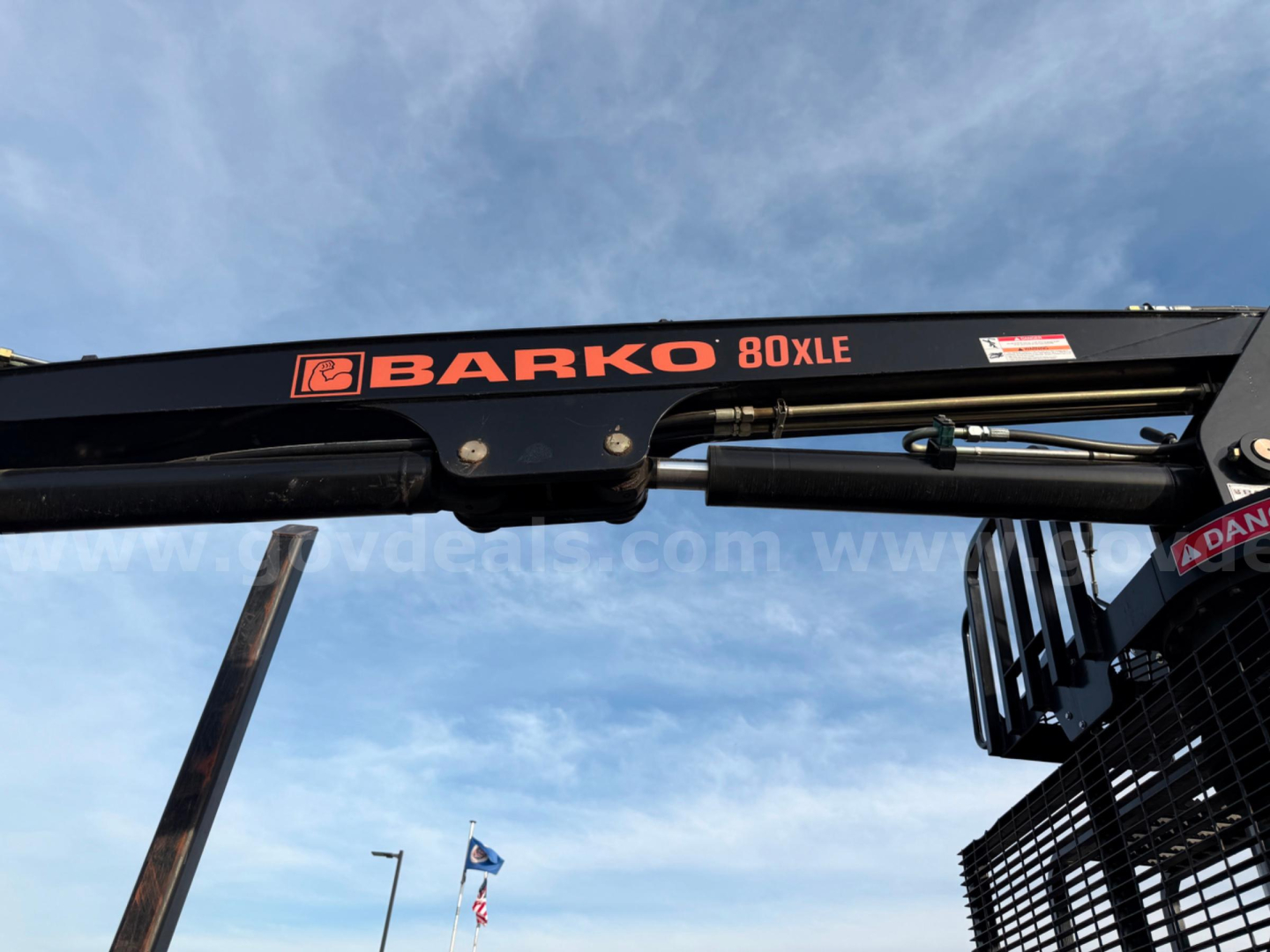 Front portion of a Mack CV713 grapple truck showing a BARKO 80XLE crane sticker on the boom and partial grapple framing.