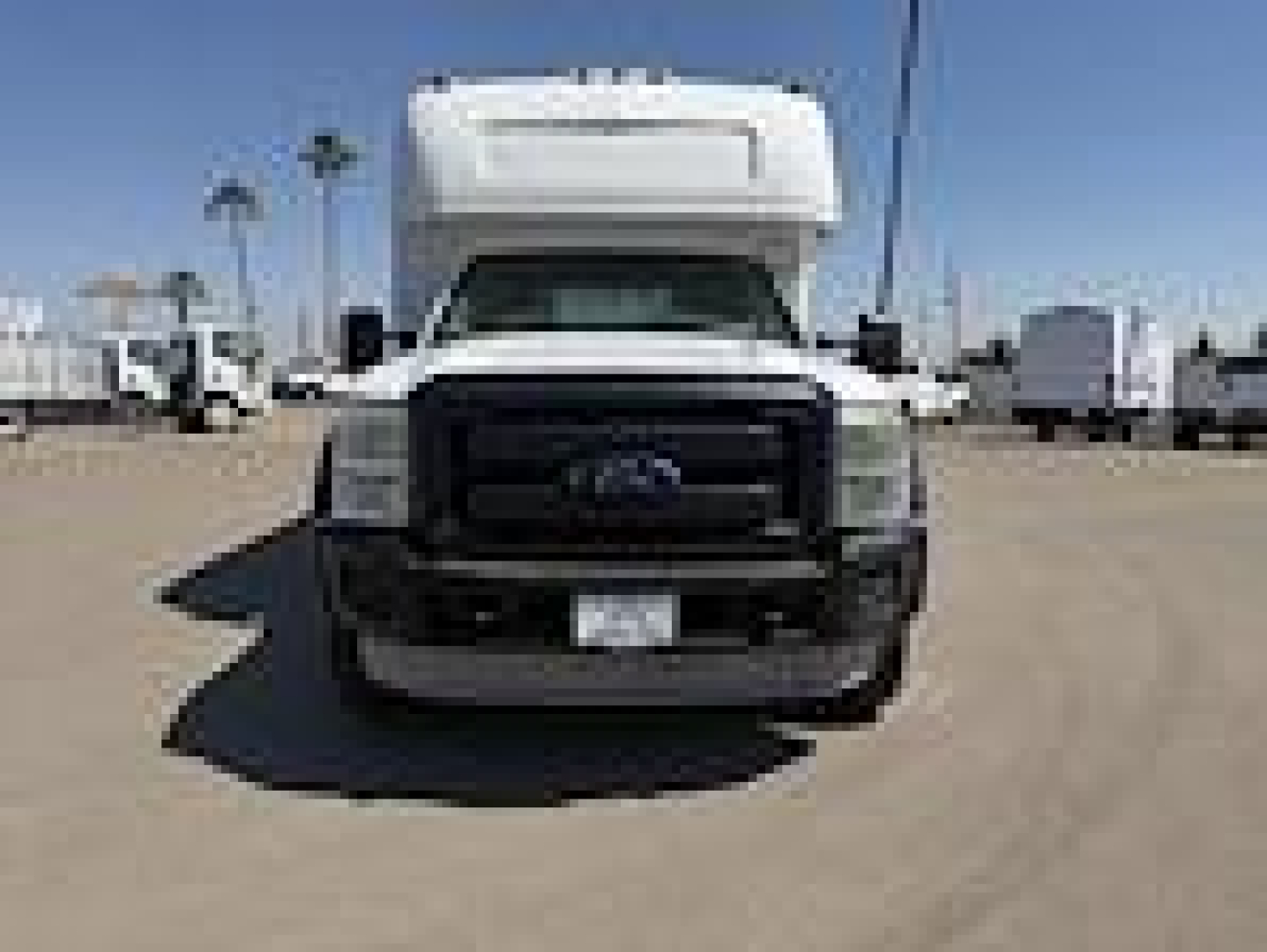 Ford F-450 front view showing large black grille, white cab, flat bumper, and license plate area.