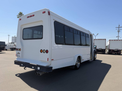 Ford F-450 bus rear-left view showing windows and bumper with hitch and exhaust pipe