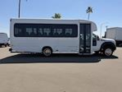 Ford F-450 bus-style shuttle showing side profile with large windowed body and entry door.