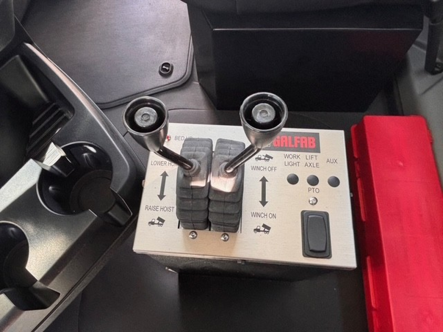 Mack GR64B control panel with joystick levers and labels showing lower raise, work light, and winch controls inside cab.