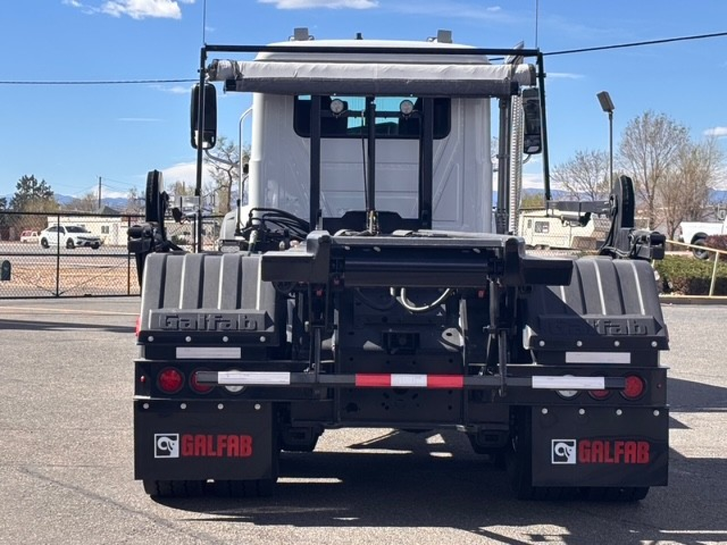 Mack GR64B roll-off truck rear view showing Galfab mud flaps and loading hitch, with taillights and hydraulic lines visible.