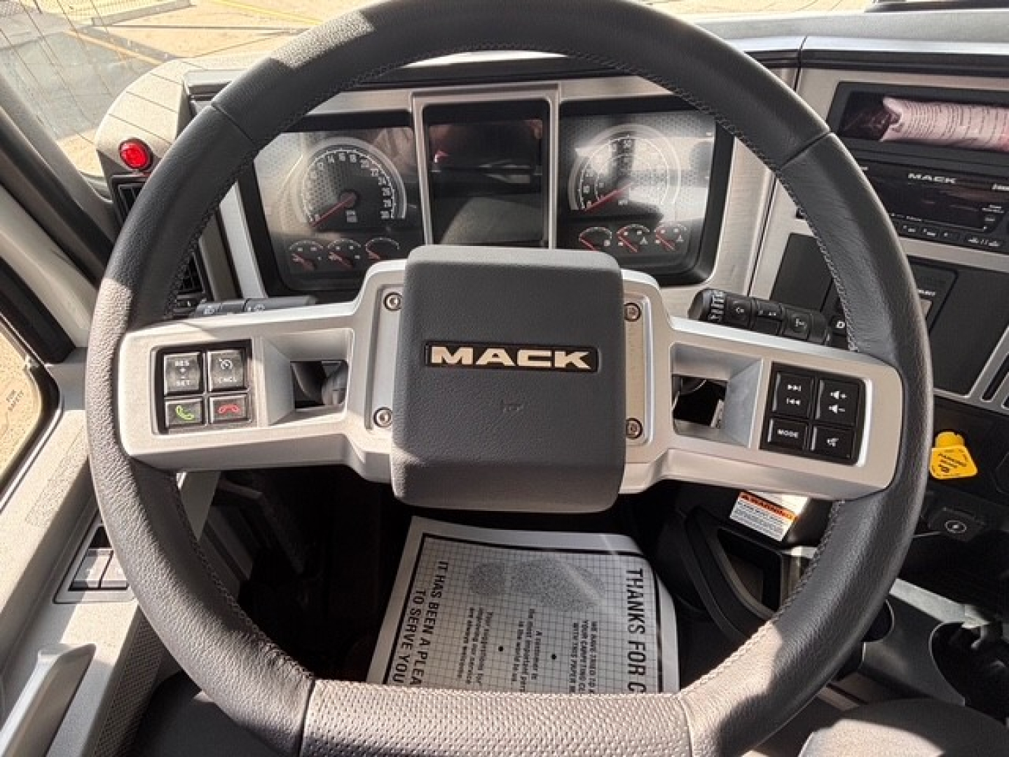 Mack GR64B truck steering wheel and dashboard with Mack logo on center hub.