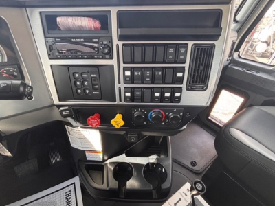 Mack GR64B dashboard view showing control panels, switches, climate controls, cup holders, and empty cup holders.