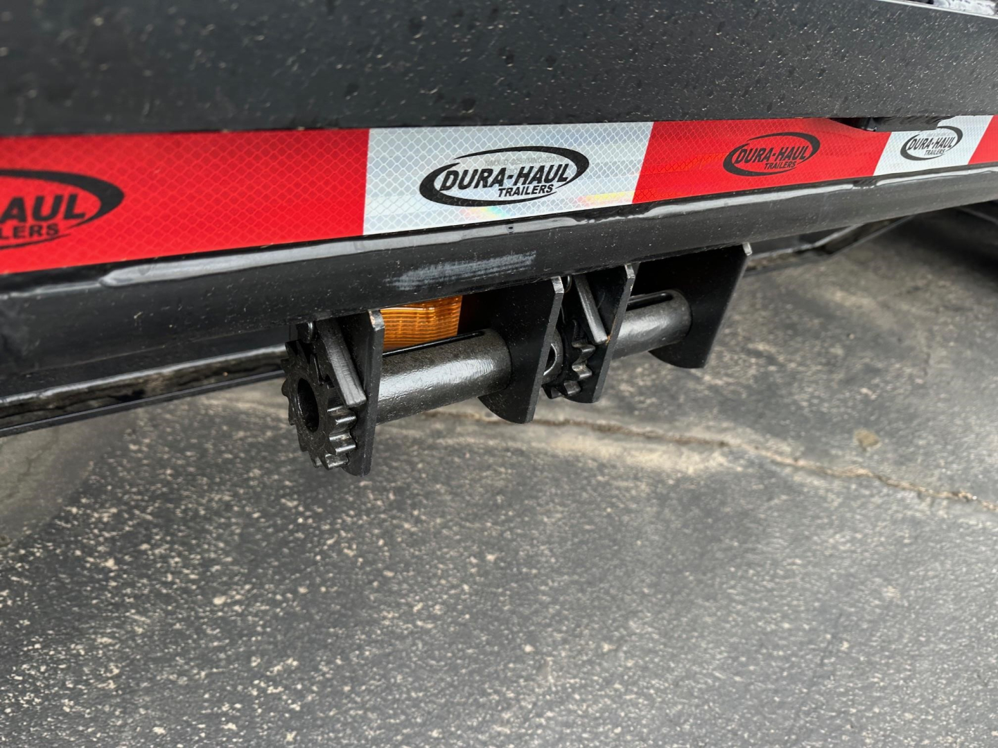 Trailer rear underside showing Dura-Haul reflective tape and hitch mechanisms, black steel frame, beavertail/flip ramp area visible.