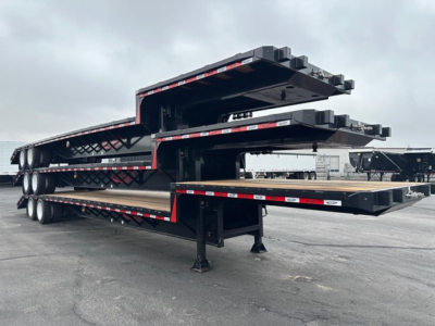 Stacked steel drop deck trailers with multiple levels and black frames, red-and-white reflective tape along the sides, support legs extended.