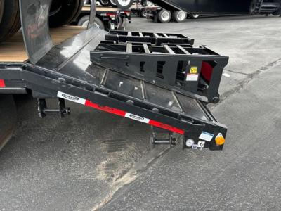 Trailer rear showing drop deck and loading ramps with metal framework and safety decals.