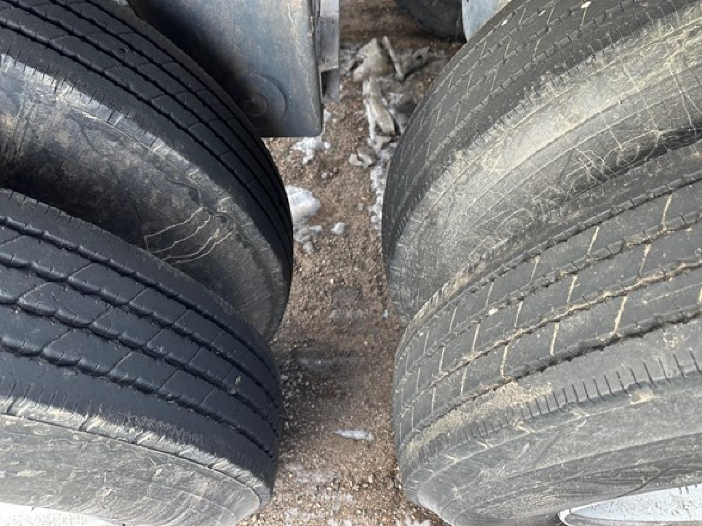 Trailer dual rear axles tires view showing worn treads and road grime on tires of a CPS 40' air ride bottom dump trailer.