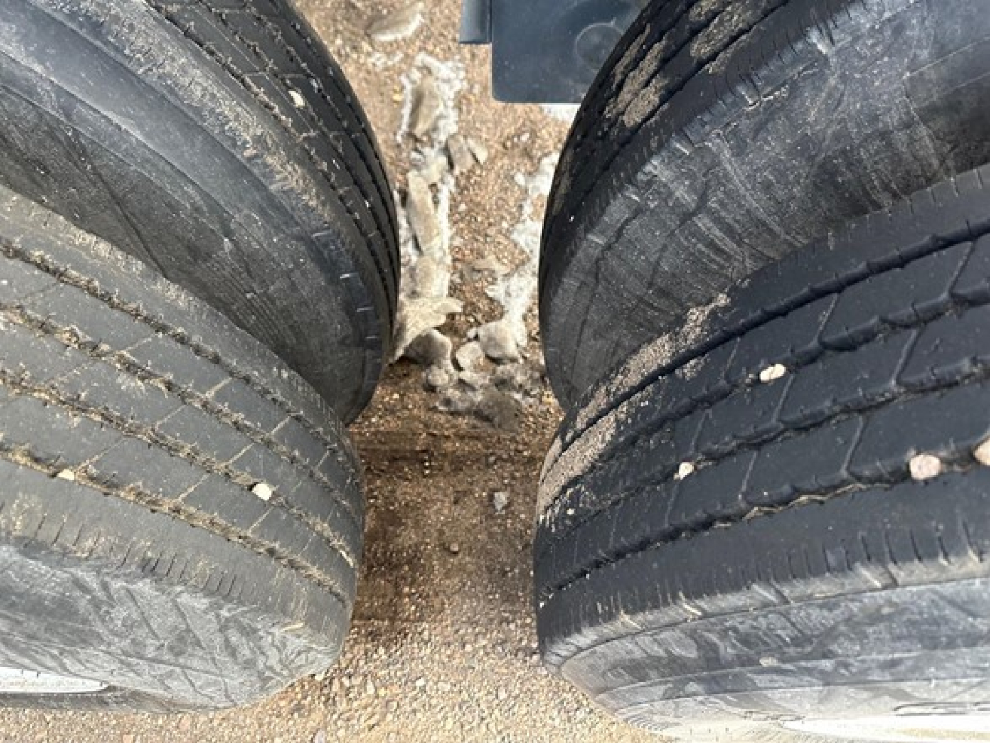 Dual rear wheels of a 2025 CPS 40' air ride bottom dump trailer showing worn tread and dirt on tires.