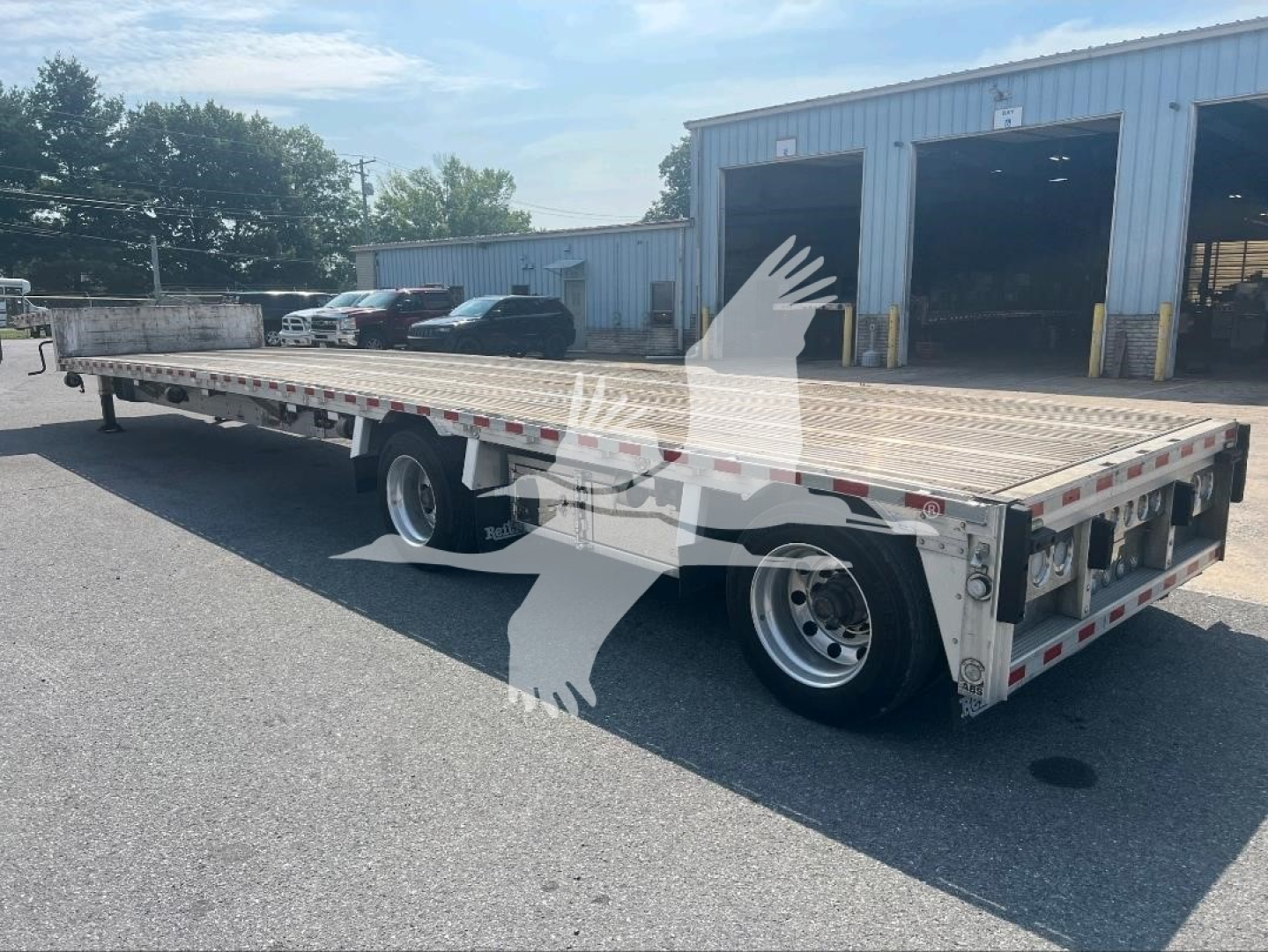 2021 Reitnouer dropdeck trailer shown in side view with dual rear axles, aluminum deck, reflectors, and open loading ramp area.
