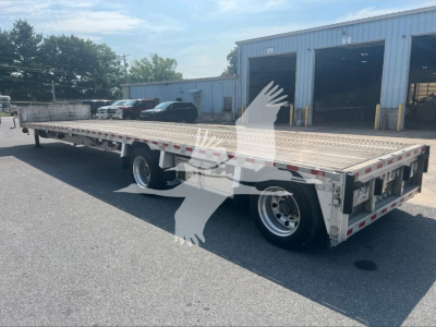 2021 Reitnouer dropdeck trailer shown in side view with dual rear axles, aluminum deck, reflectors, and open loading ramp area.