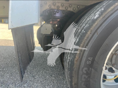 Trailer wheel area showing dual tires with mudflap and suspension hardware from a 2021 Reitnouer dropdeck trailer.