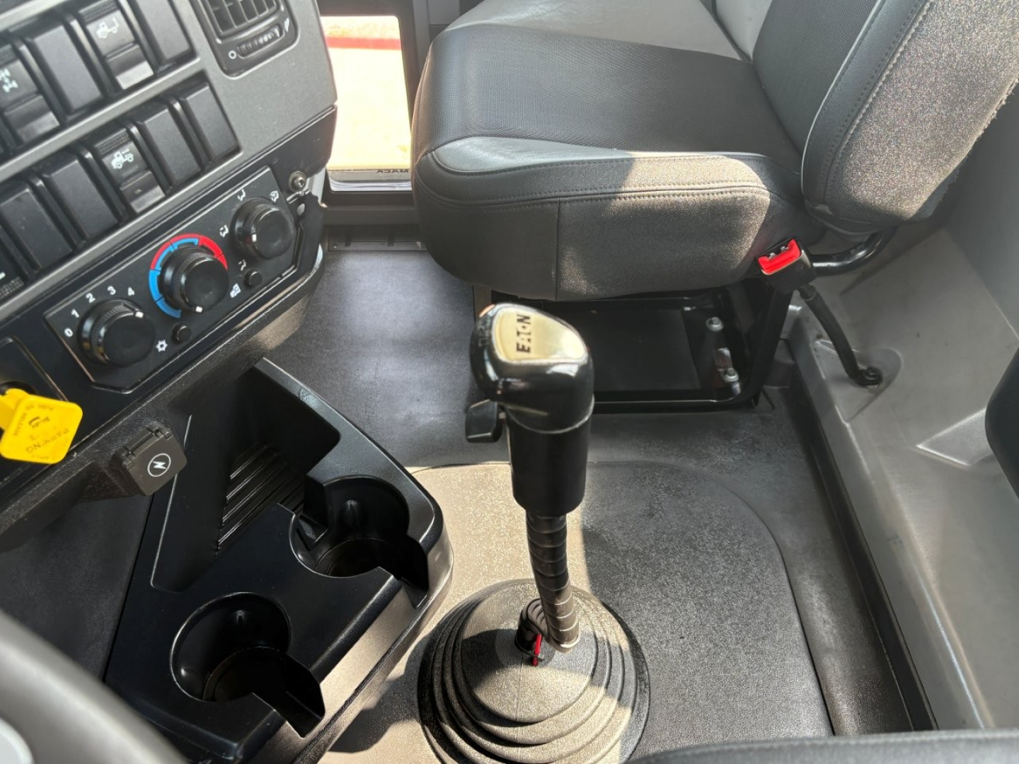 Cab interior of a 2020 Mack PI64T truck showing gear shift lever, center console with cup holders, and dashboard controls.
