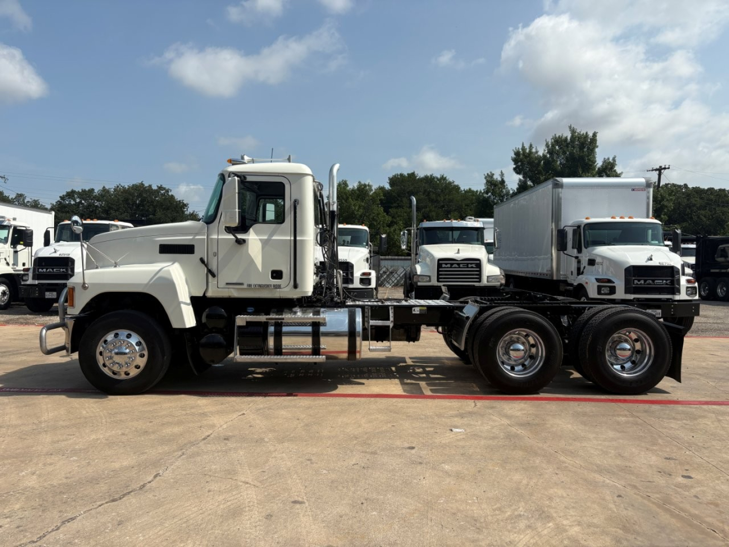 Truck chassis side view showing Mack PI64T cab and chassis with dual rear axles, white cab, chrome fuel tanks, and spring suspensions.
