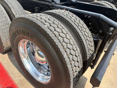 Mack PI64T truck axle and dual tires with Bridgestone tire branding and chrome rim, showcasing heavy-duty wheel assembly.