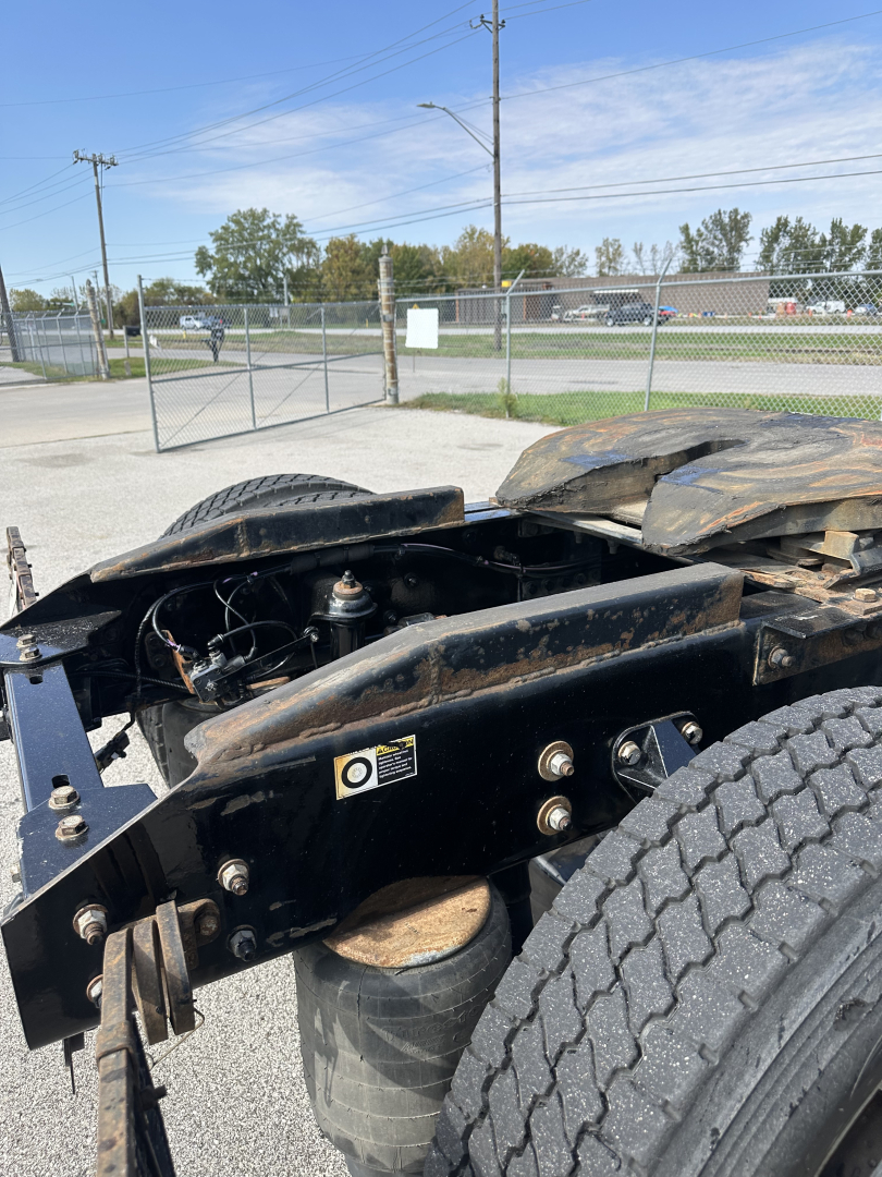 Truck chassis and dual rear wheel area of a 2022 Kenworth T680 in-service condition, showing frame rails, suspension air bags, and labeling near the cab area.