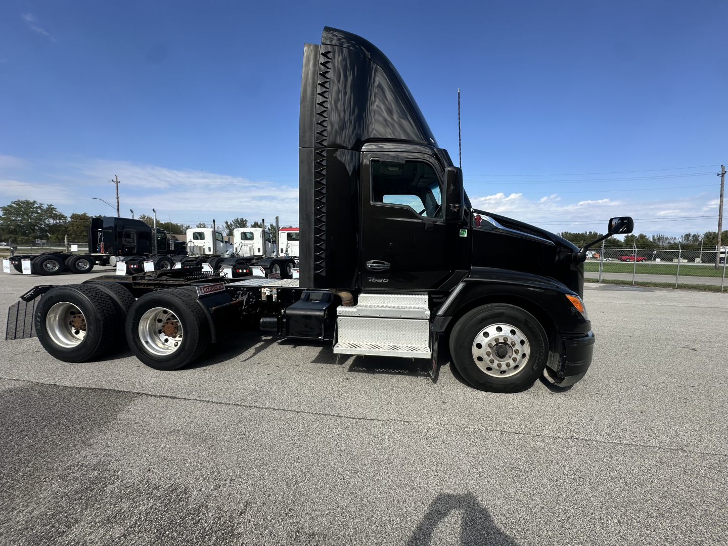 Kenworth T680 tractor unit side view showing cab with tall sleeper fairing and black paint, side steps, fuel tanks, and rear wheels; text on the truck not legible.