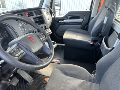 Kenworth T680 cab interior showing steering wheel and driver seat with dashboard gauges.