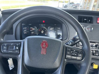 Dashboard and steering wheel of a Kenworth T680 cab showing instrument cluster and steering wheel emblem KW in center.