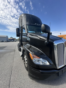 Kenworth T680 daycab front-right view showing cab and grille with chrome bumper and large mirrors.