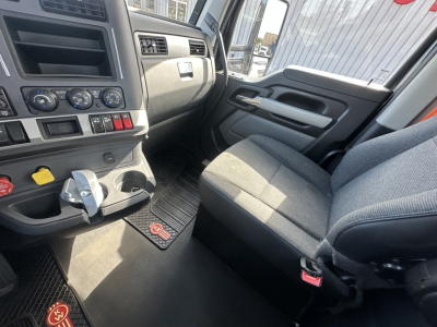 Kenworth T680 cab interior view showing driver seat and dashboard with control switches and floor mats.