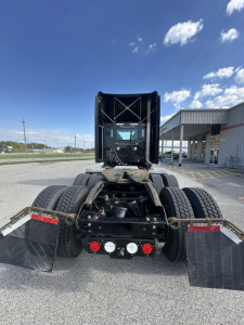 Kenworth T680 tractor rear view showing dual rear wheels and mud flaps, with five circular gauges and connectors on the chassis undercab, and rear lights visible.