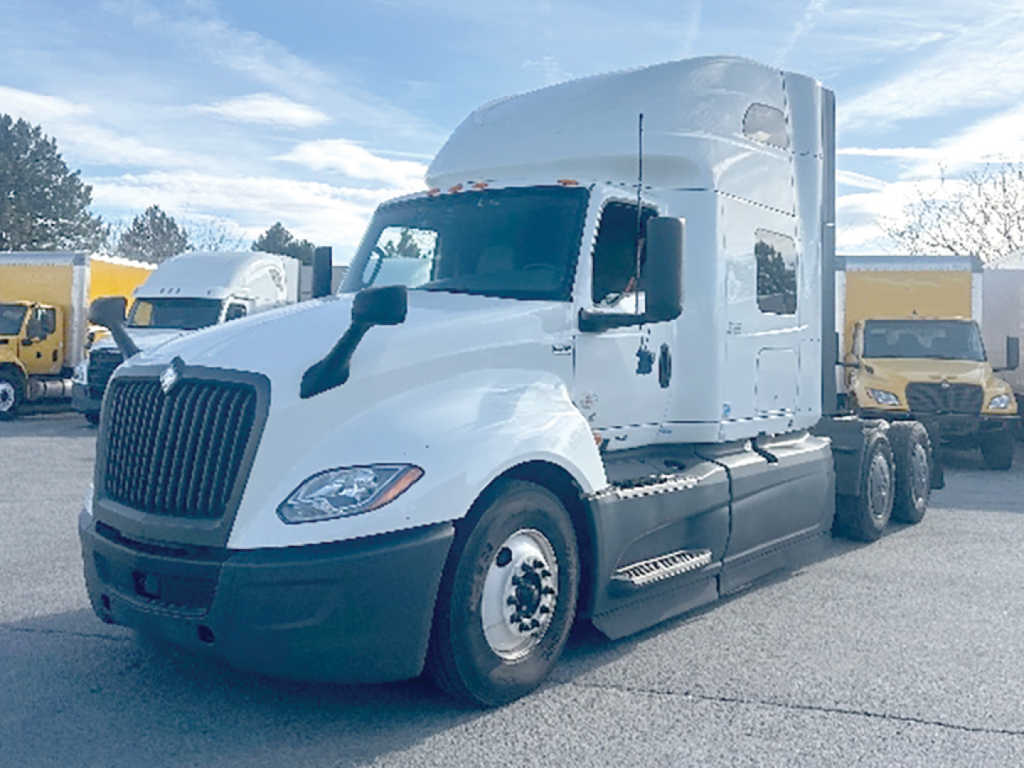 International LT625 truck tractor in white, side view showing cab, high sleeper, and tandem rear axles with black chassis.