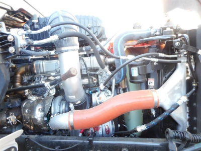 Engine bay of a Western Star 47X dump truck showing large orange coolant hose and various hoses, filters, and metallic components.