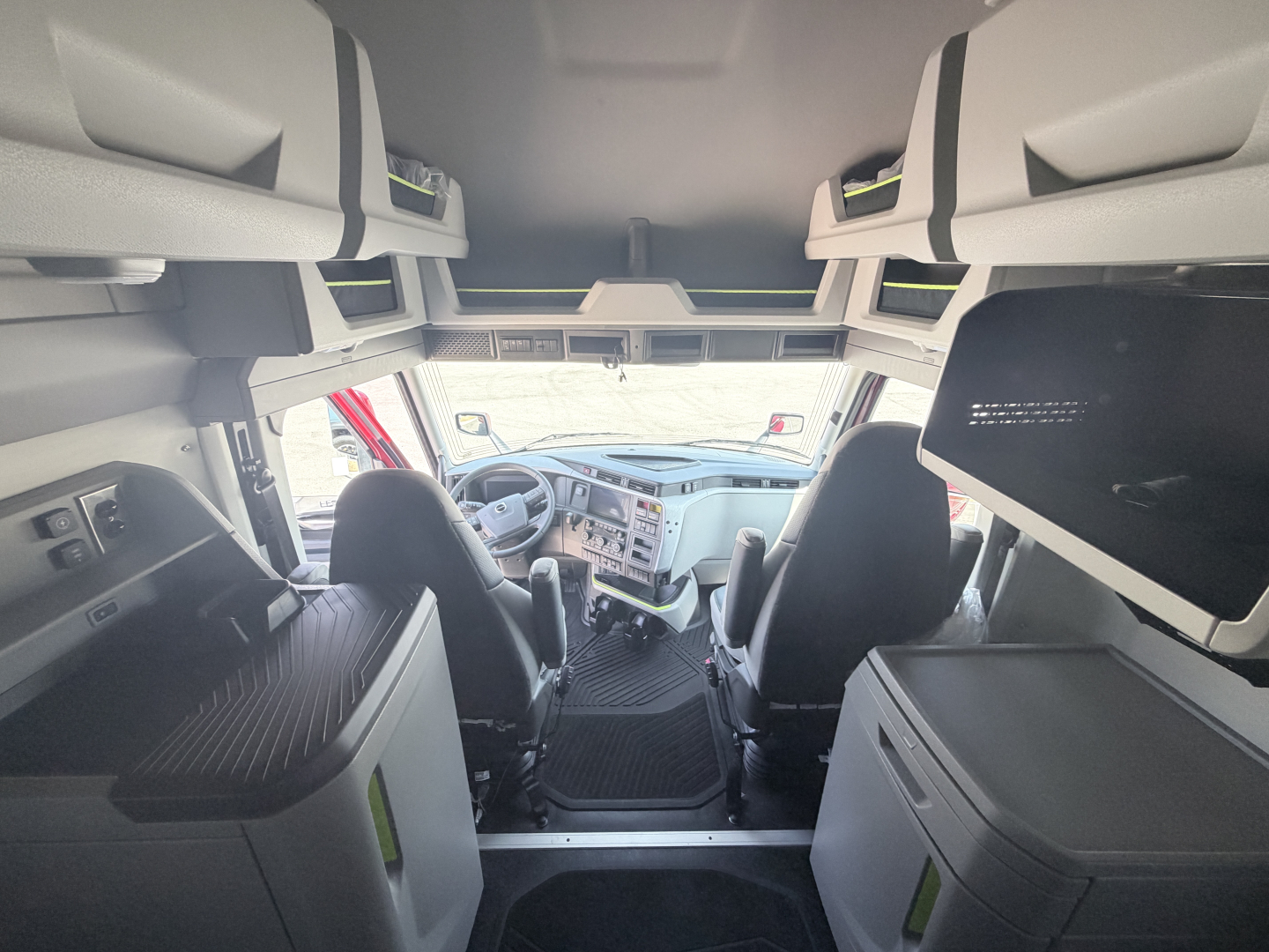 Cab interior of a Volvo VNL64T860 truck with overhead storage and dual sleeper bunks visible, front dash and steering wheel in view.
