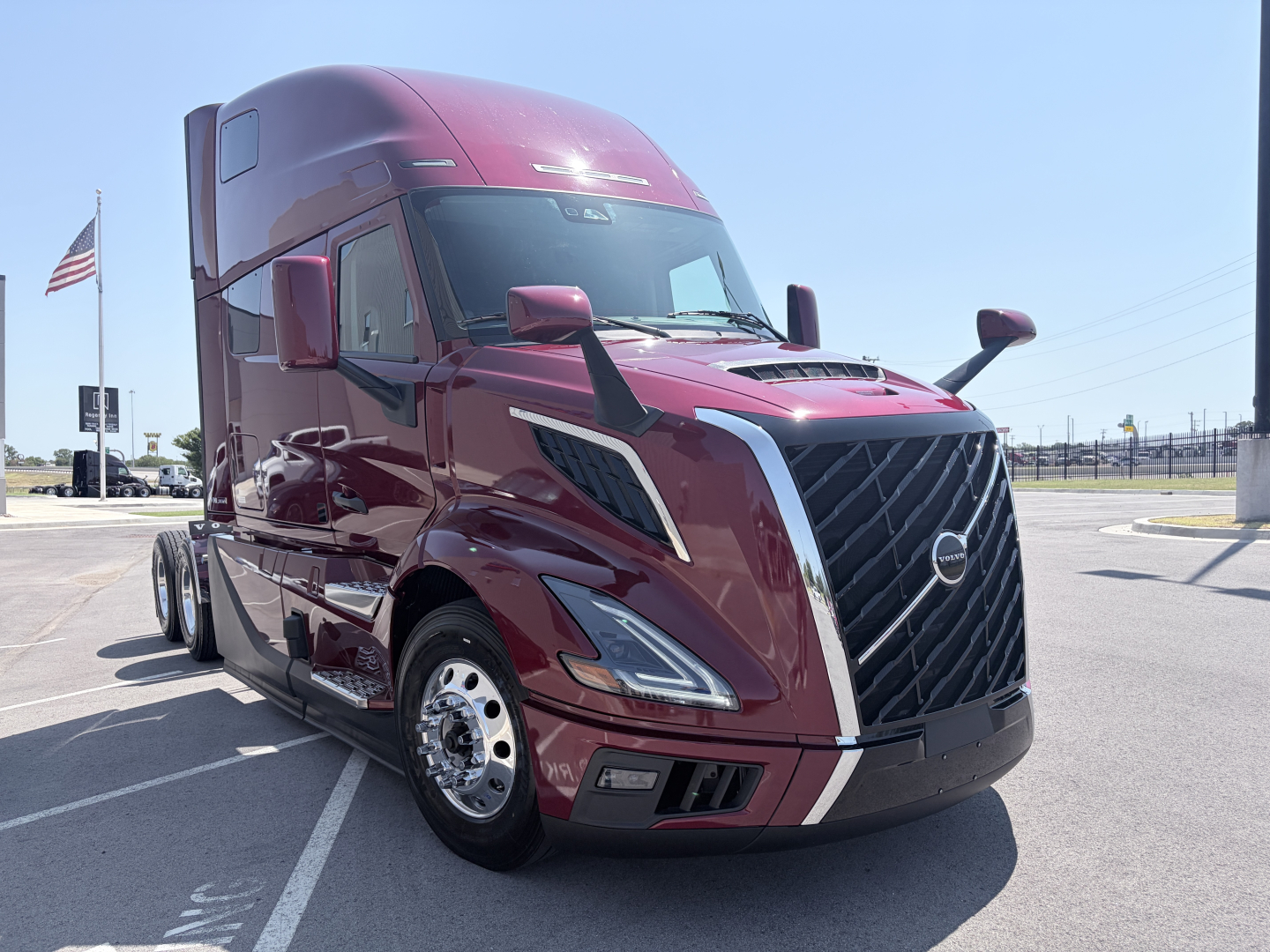 Volvo VNL64T860 tractor truck in maroon showing front grille and headlights, side view mirrors, chrome wheels; cab-over design with aerodynamic features.